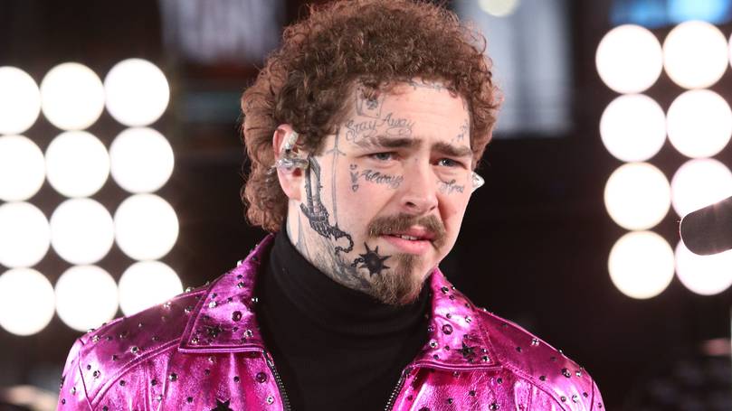 Post malone wearing a shocking pink colored funky jacket on a black turtle necked shirt