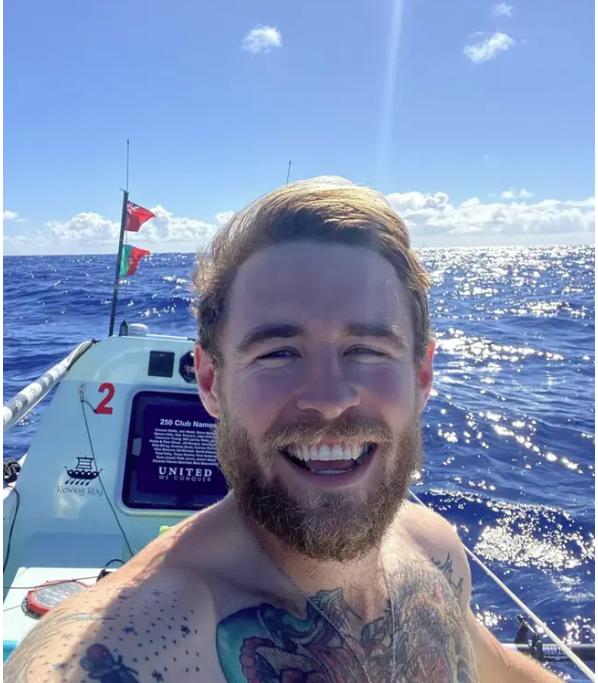 Jack Davis smiling while taking a selfie and sailing on his boat