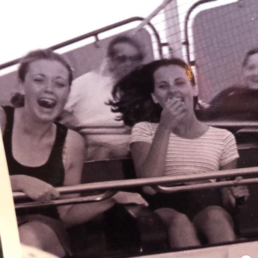 Gemma wearing a black shirt and grey shorts and her friend wearing striped white shirt enjoying roller coaster ride