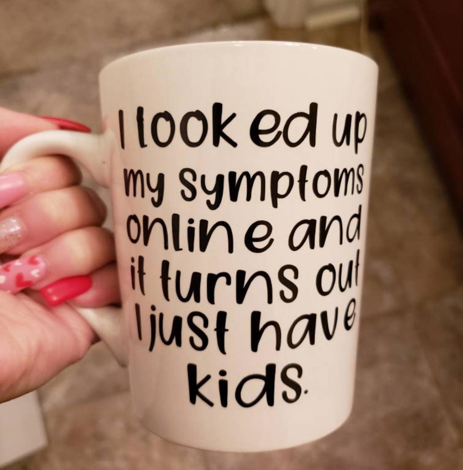 Black colored 'I Looked Up My Symptoms Online And It Turns Out I Just Have Kids' printed on a pink design white mug