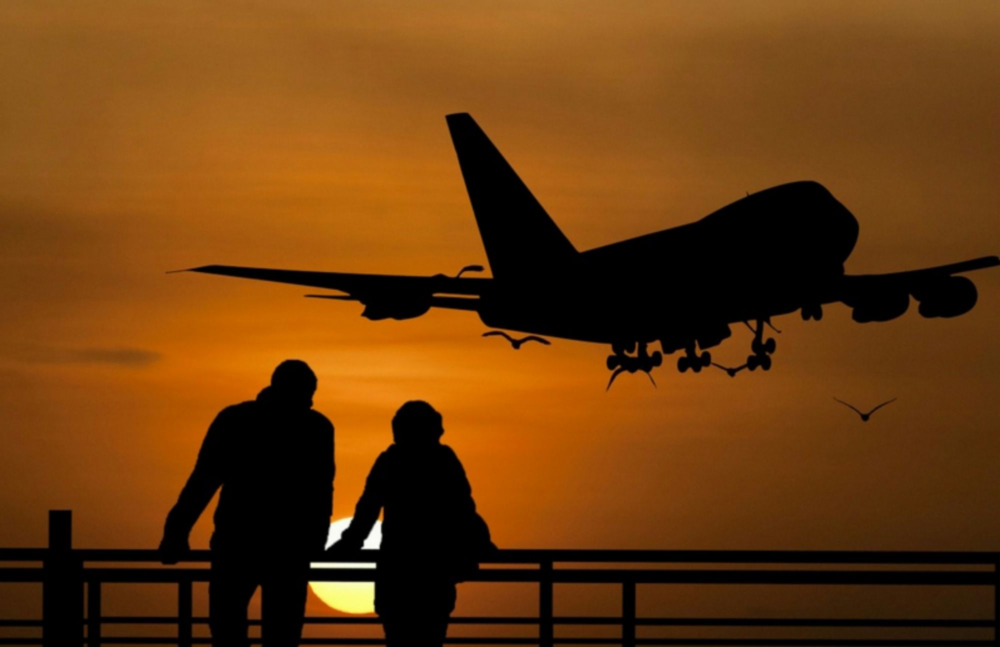 A couple and an airplane in the air in a silhouette shot