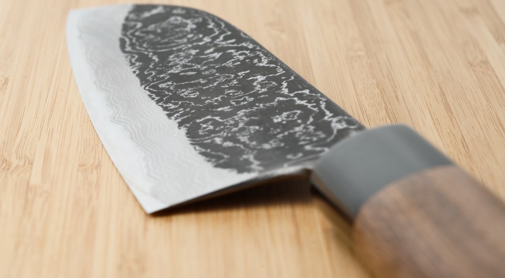 An angular view of Japanese Damascus Kitchen Knife placed on a wooden surface