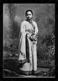 Black and white pic of an indian doctor women wearing a white saree and her hair tied in a bun