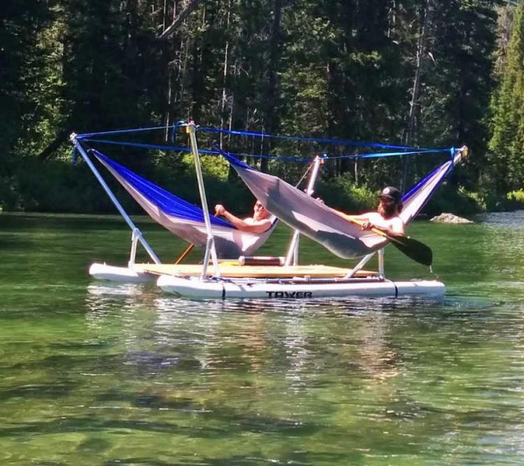 Two men resting in the blue-grey boat hammock in the lake