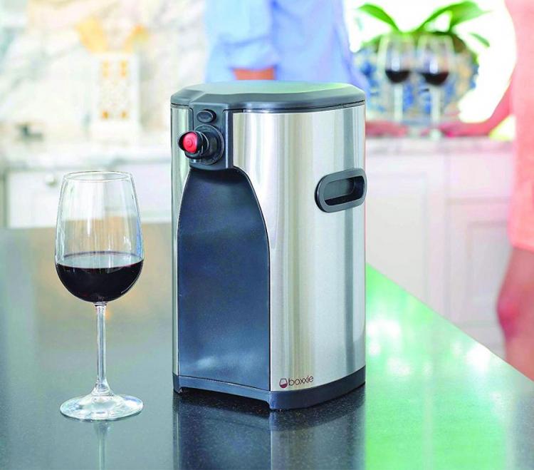 Black and stainless steel wine dispenser and a half-filled wine glass on a black surface