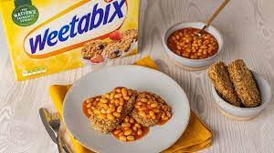 Yellow colored Weetabix pack along with Weetabix with beans on a white plate