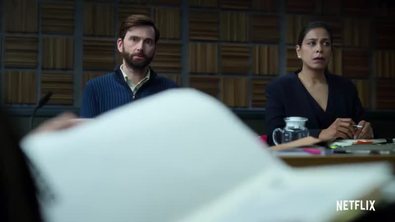 A bearded man and a girl wearing a blue shirt sitting at the investigation table