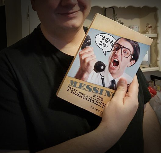 A man holding a messing with telemarketers book