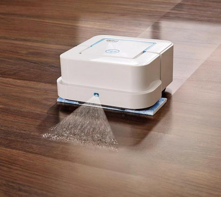 White square-shaped robotic carpet cleaner on a dark brown wooden floor
