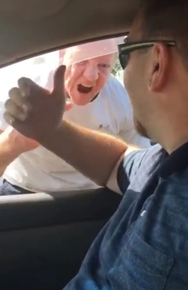 A white shirt wearing old man screaming at the man wearing a blue shirt