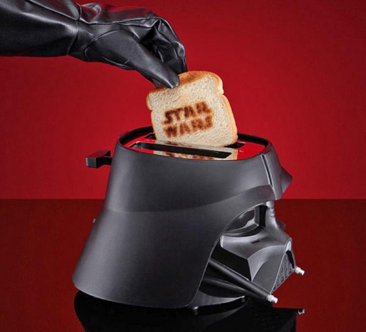 Black colored star wars darth vader mask themed toaster that prints star wars on toast on a dark red colored surface
