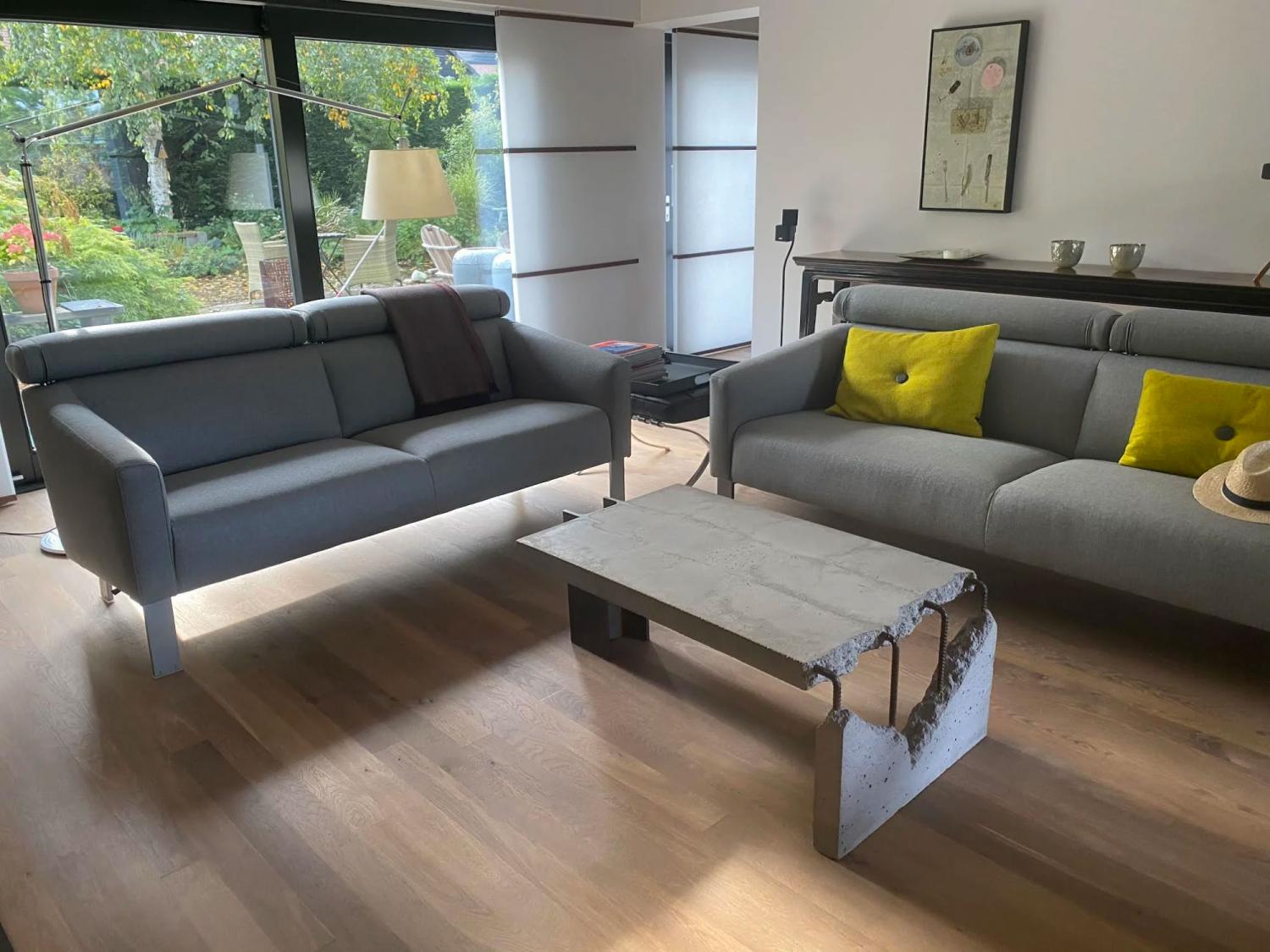 White-grey ceramic concrete coffee table with two grey sofa on a wooden floor