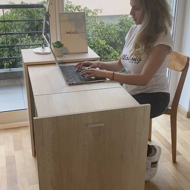 A girl sitting next to a skin-brown colored wooden secret folding desk