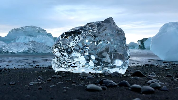 A close up shot of a giant ice diamond on black sand on diamond beach