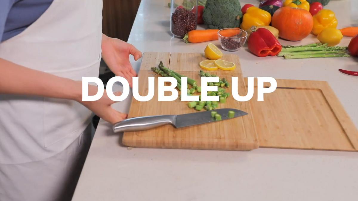 Double cutting boards in a Smart Chop Smart Cutting Board on a white kitchen top with some vegetables on it