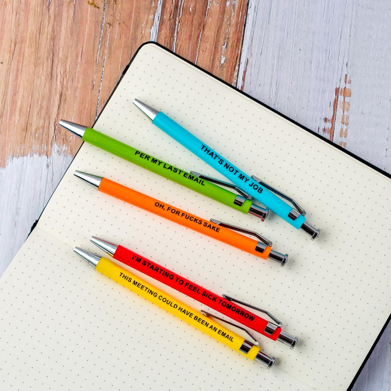 Red, yellow, green, blue, and orange colored Offensive Office Pens on a white notebook page