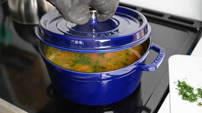 Vibrant blue dutch oven filled with soup on a stove