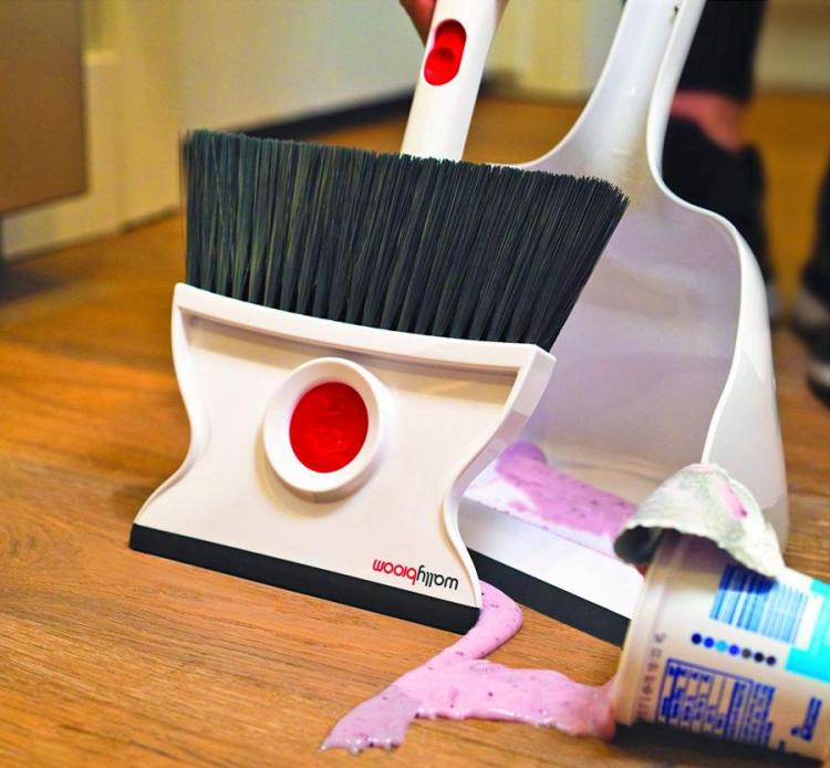 Red and white double-sided broom cleaning pink smoothie from brown wooden floor