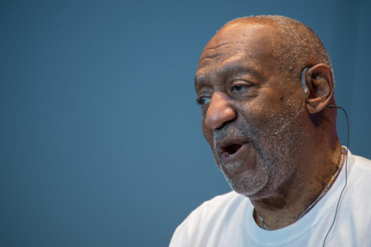 Bill Cosby speaking thru a mic on his left ear