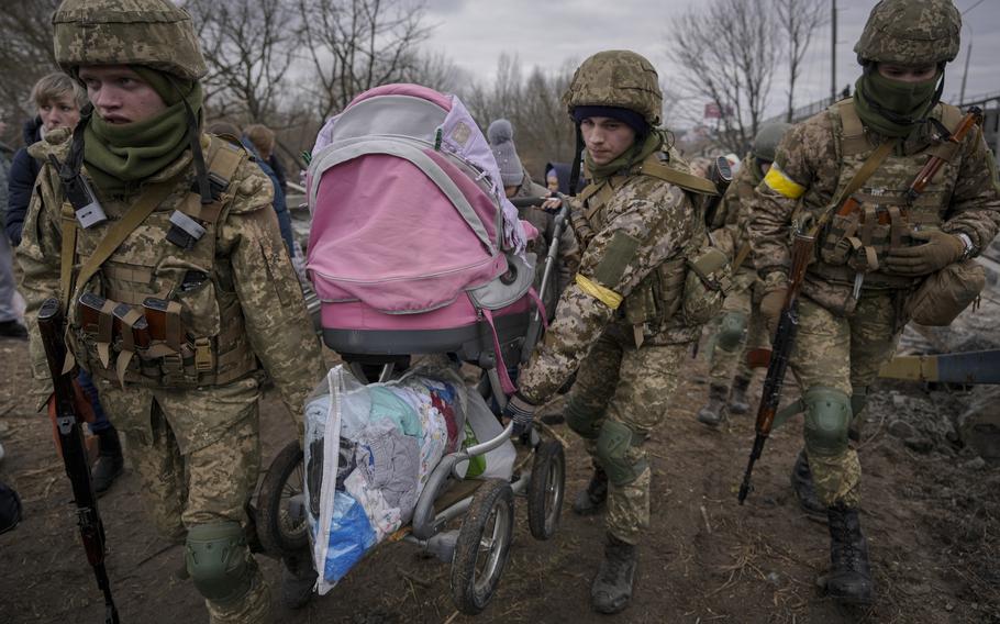 Ukraine soldiers holding baby stroller and pile of clothes
