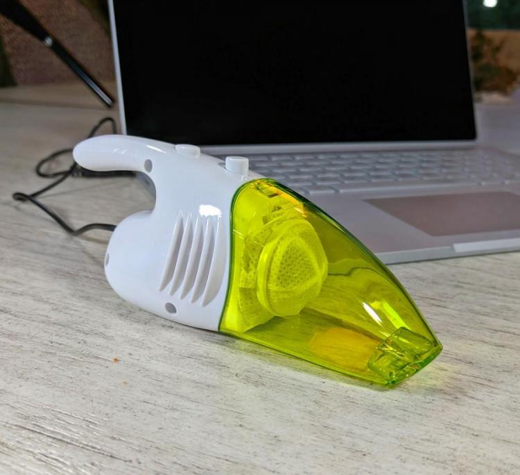 Transparent green and white bottomed cleaner placed in front of laptop on a wooden table