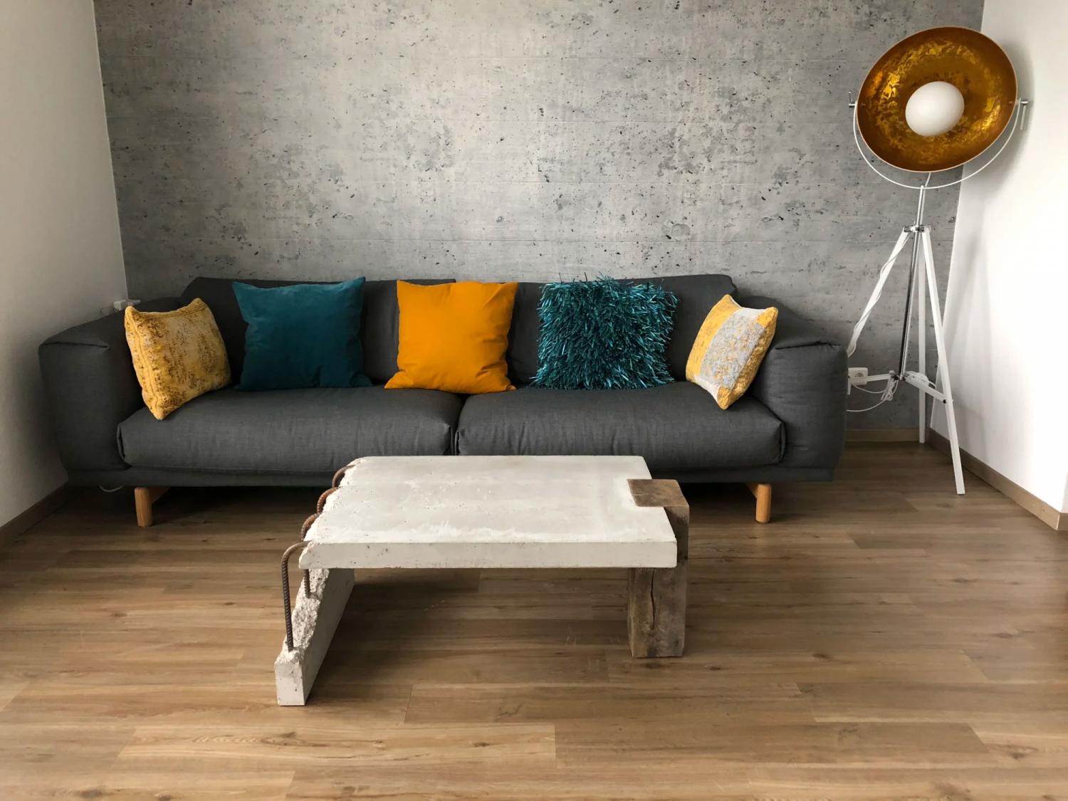 White ceramic concrete coffee table besides a grey sofa on a wooden floor