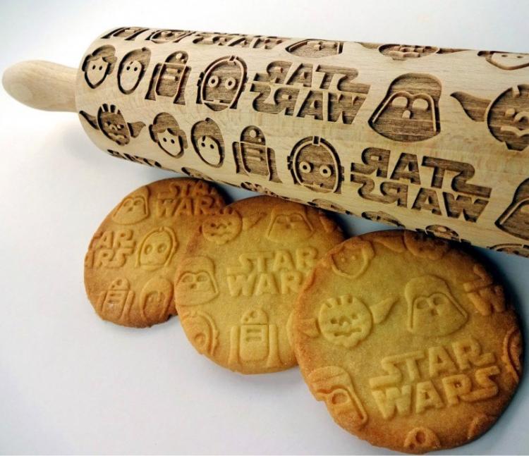 Star wars themed wooden rolling pin with some baked cookies on a white surface