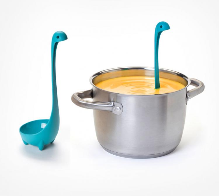A blue-colored dinosaur-shaped cooking utensil in a yellow soup pot