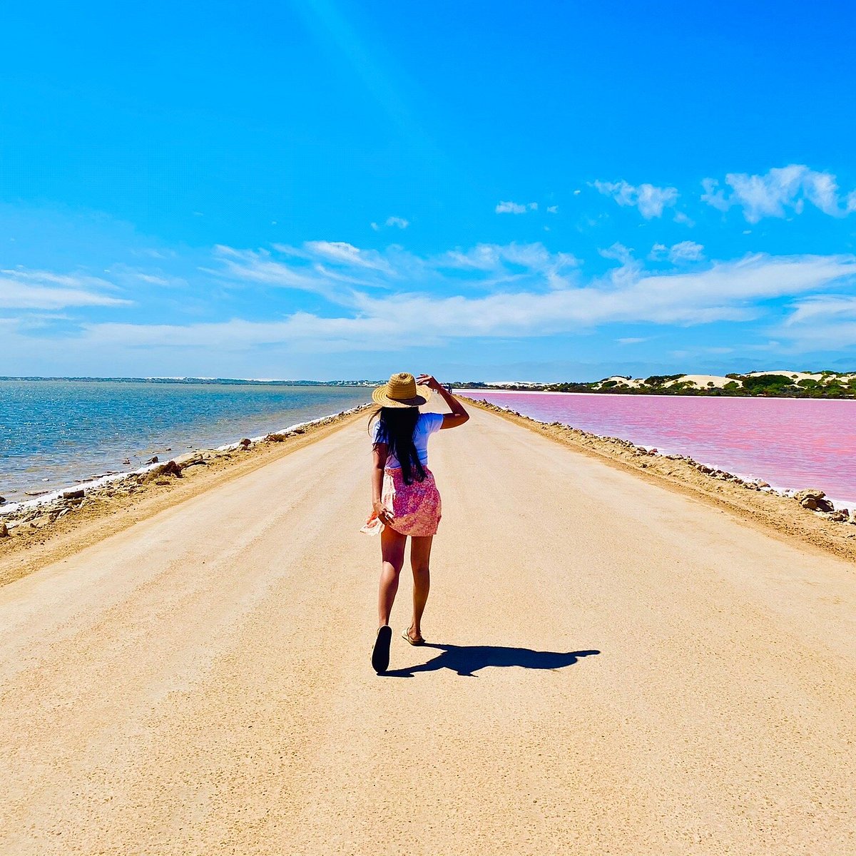 A girl walking on the road of Pink Lake SA