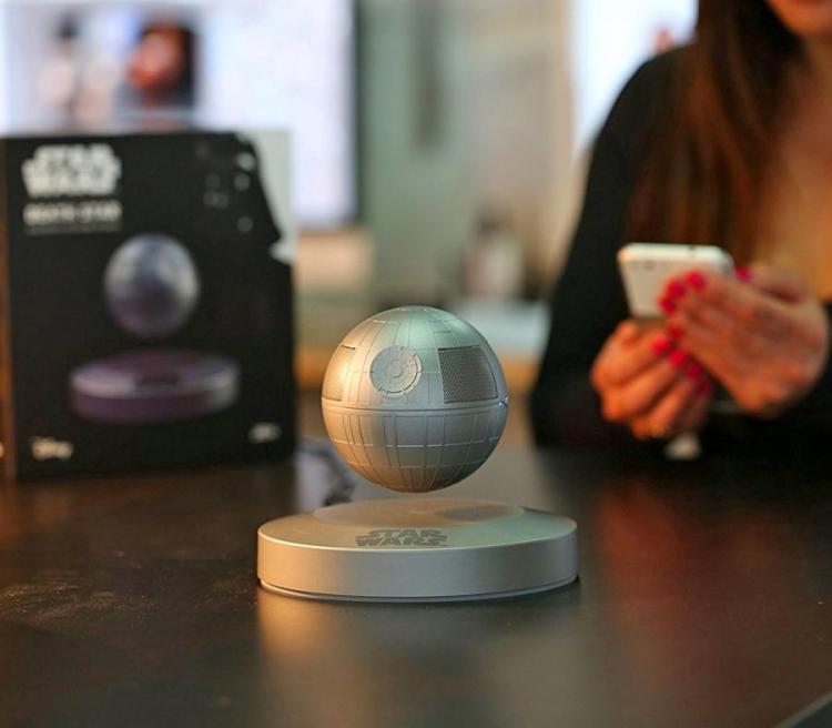 Grey colored star wars death star themed Bluetooth speaker on a dark brown table