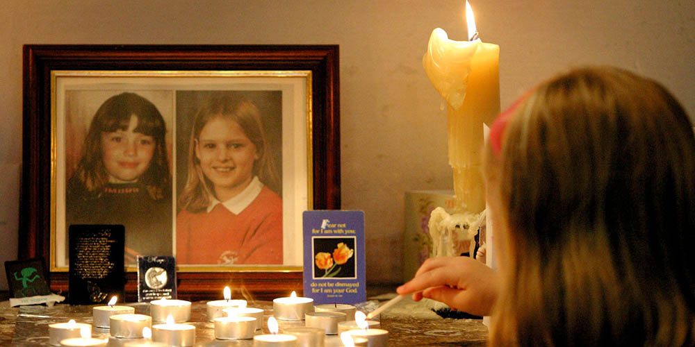 Holly and Jessica pictured on a table with some candles on it and a woman lighting the candles