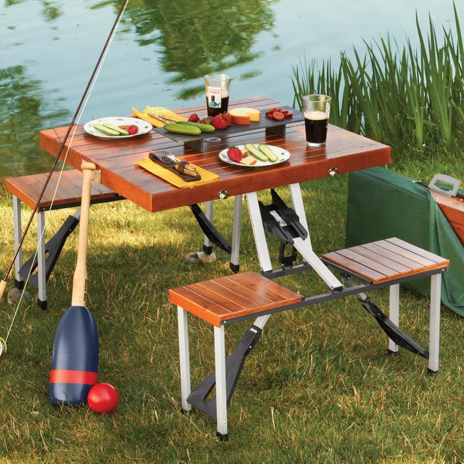 Brown colored Wooden Picnic Table Folds Into a Briefcase with some picnic stuff on the grass near lake