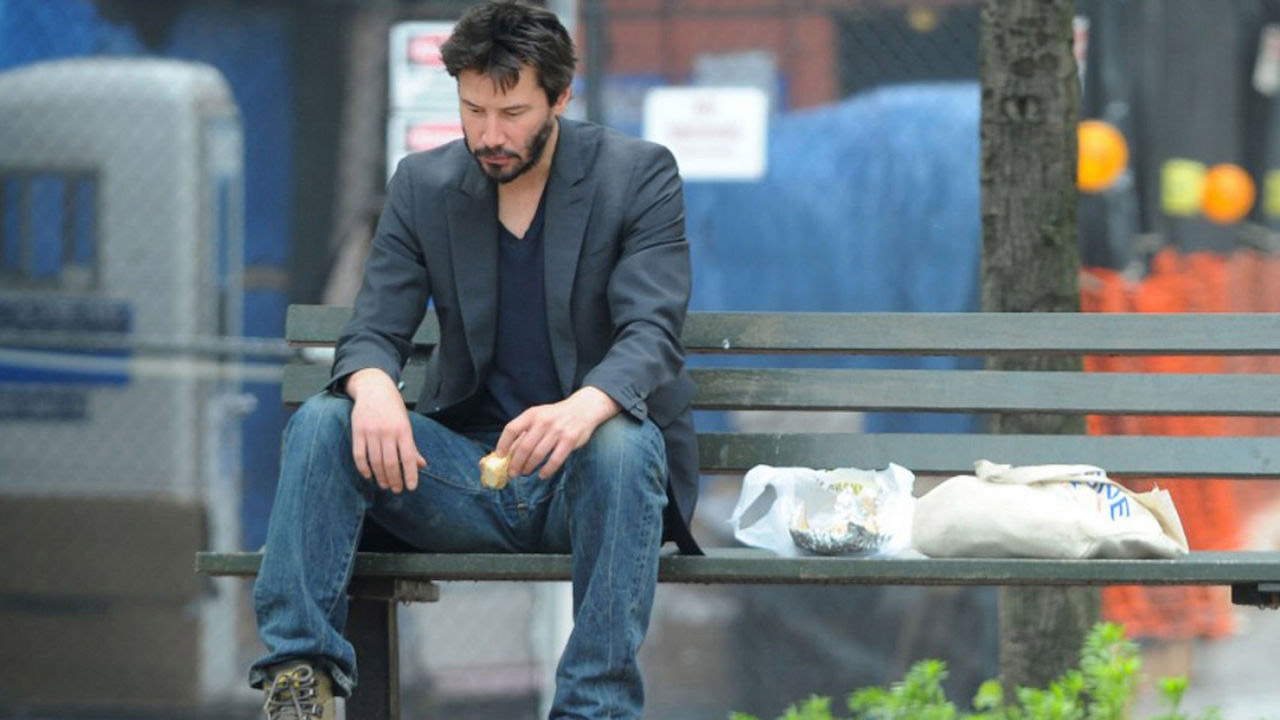A sad man eating while seating on the bench