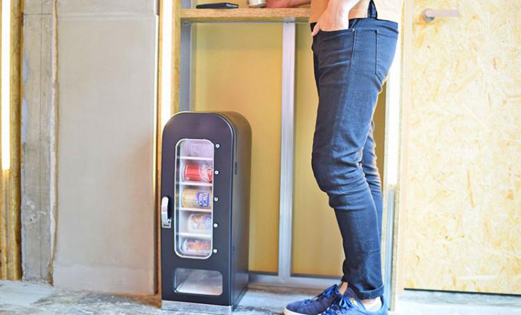 A man wearing blue jeans standing next to a black Personal Mini Vending Machine