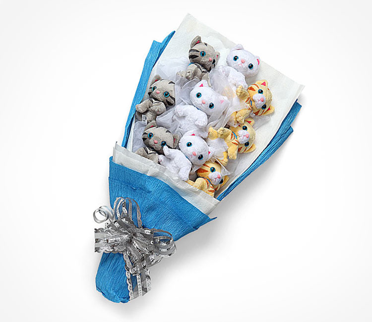 Grey, brown, and yellow colored plush kitten toys in a blue wrapping paper with a grey ribbon on it
