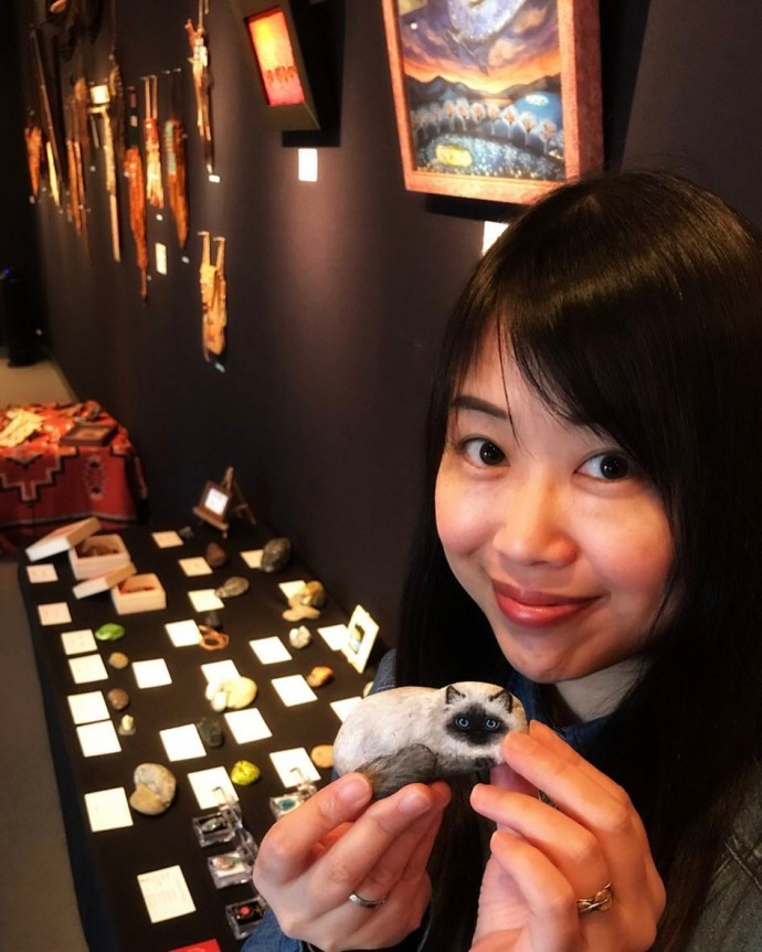 Akie nakata holding a grey-white cat painted on a stone
