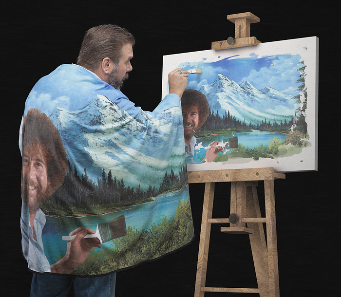A man painting famous bob ross while wearing a bob ross' painting blanket 