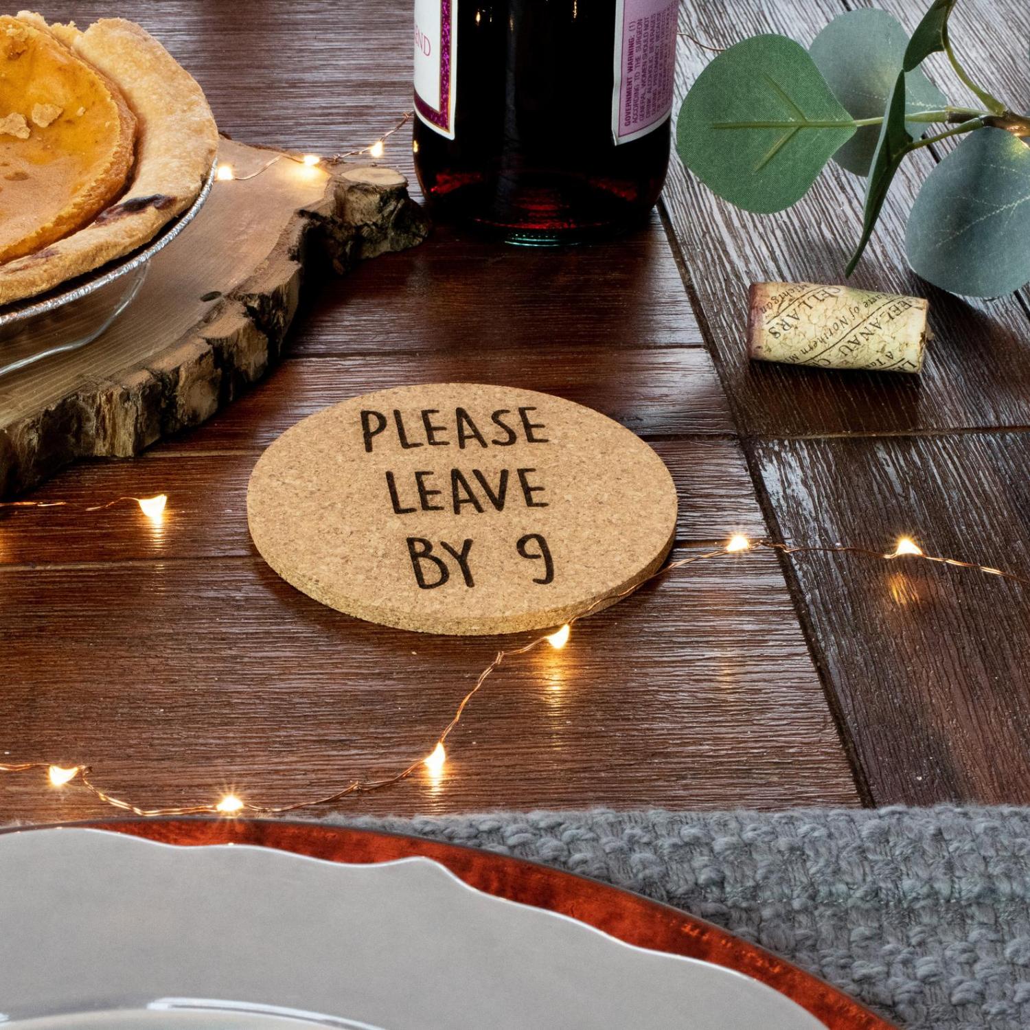 A round please leave by 9 coasters on a wooden table along with half pumpkin pie in a pie pan and a wine bottle on the table