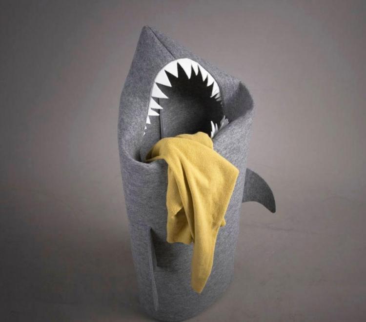 A giant grey shark laundry hamper with a yellow cloth piece on it