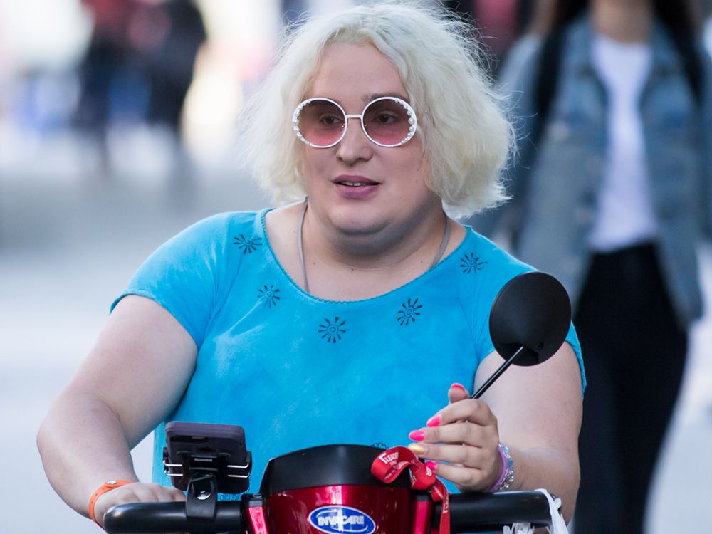 A trans woman in a motorcycle wearing sunglasses in blonde hair