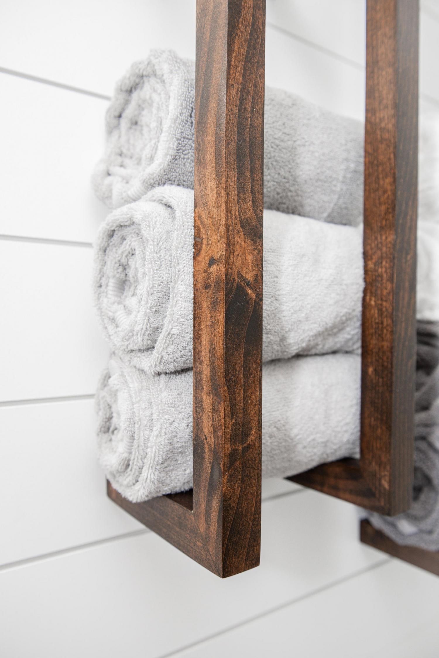 Brown wooden towel rack on a white wall