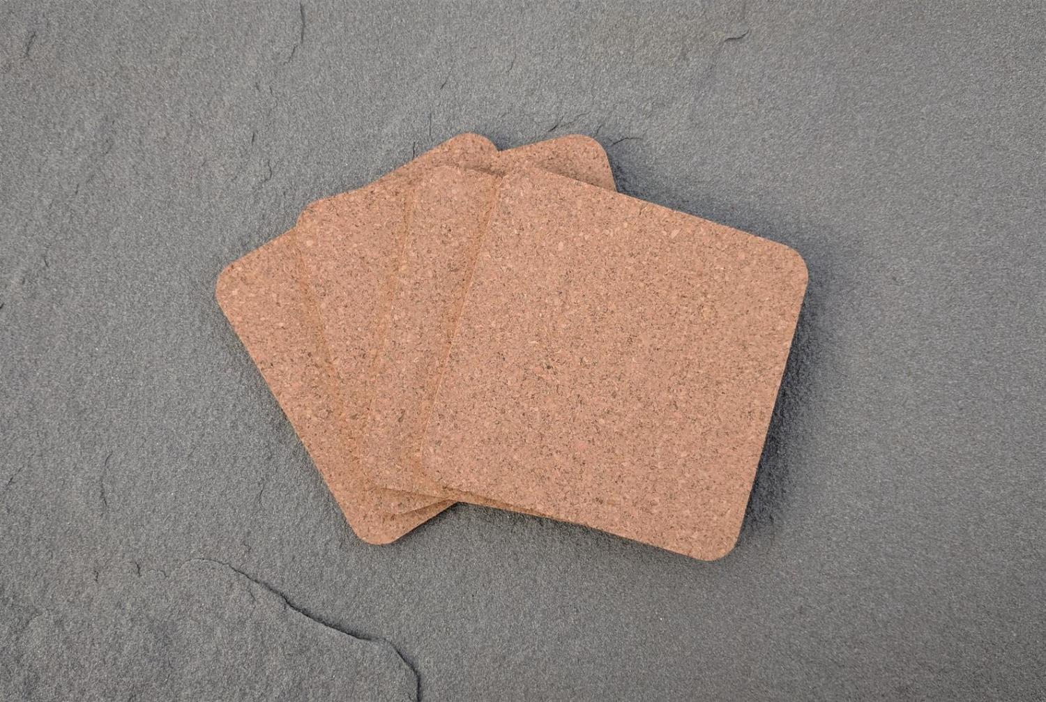 Square shaped cork coasters on a grey concrete surface