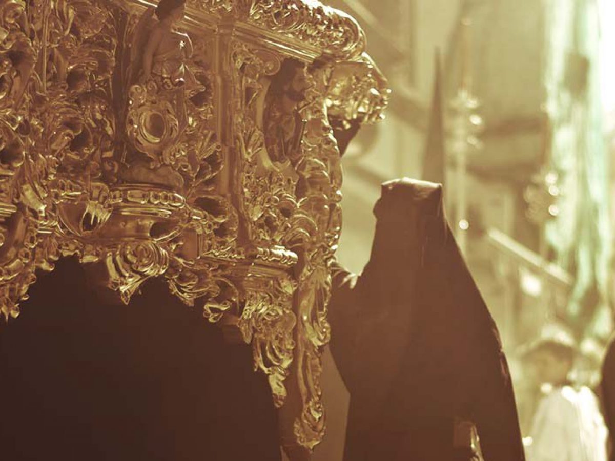 A man weraing a black cloak carrying a golden float