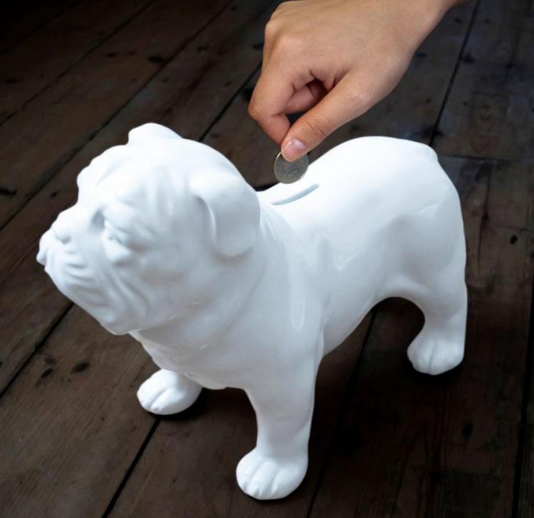 White ceramic bulldog coin bank on a dark wooden surface