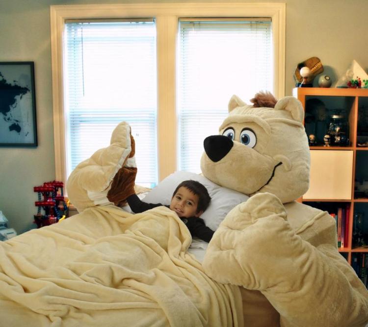 A child resting in a skin-colored giant bear bed