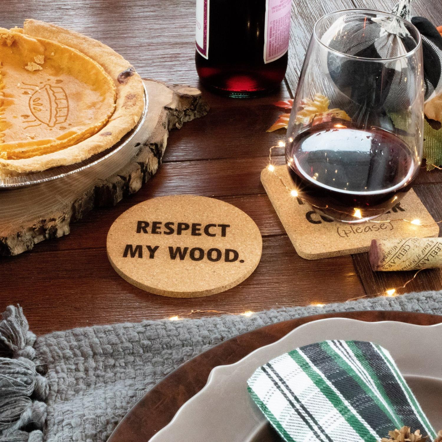 Respect my wood cork coaster  on a wooden table along with half pumpkin pie in a pie pan and a less than a half-filled wine glass on the table
