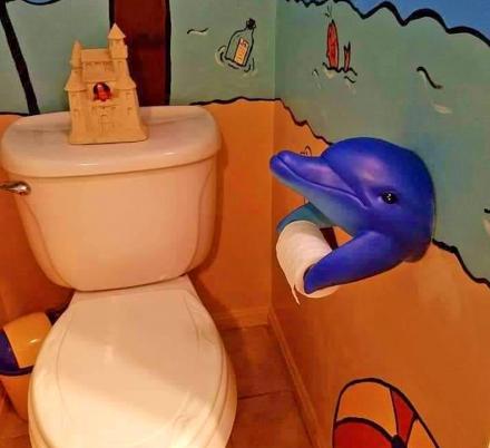 Blue Dolphin Toilet Paper Holder on a beach themed wall of the bathroom