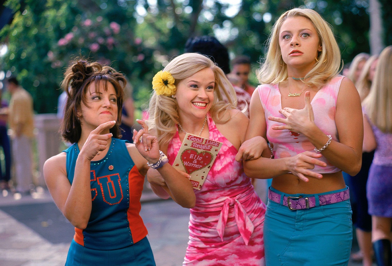 Three girls enjoying a party, one girl wearing a blue top, one girl wearing a pink and white dress, and the other wearing a pink and white top with a blue skirt