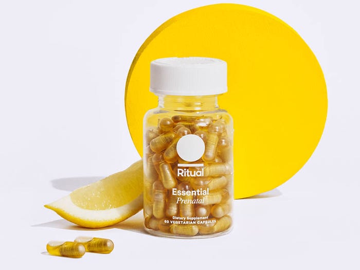 Golden multivitamin capsules in a bottle along with a slice of lemon