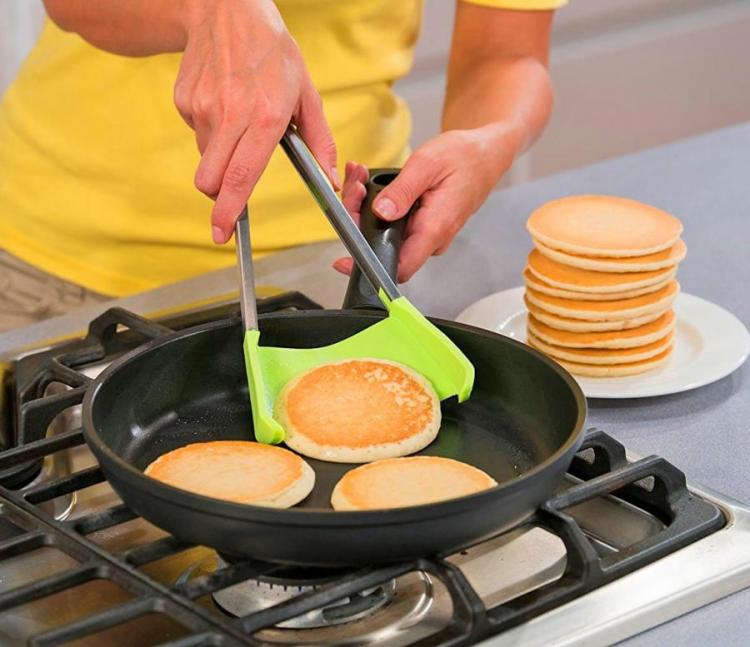 A girl wearing yellow shirt flipping pans with the green-colored; a stack of cooked pancakes on the white ceramic plate